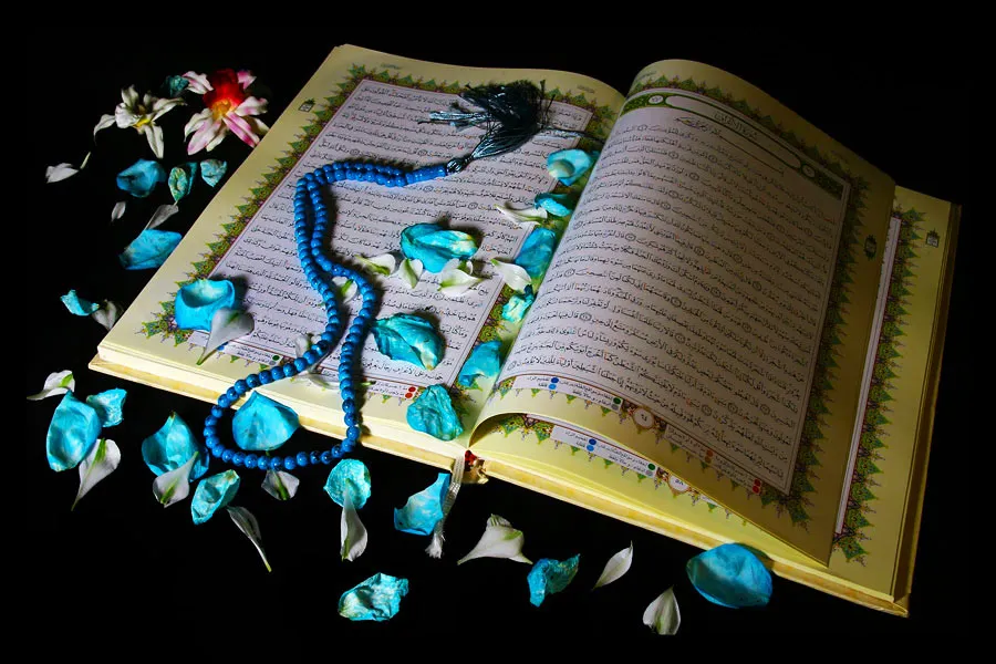 Mushaf Al Quran terbuka dengan tasbih di atasnya