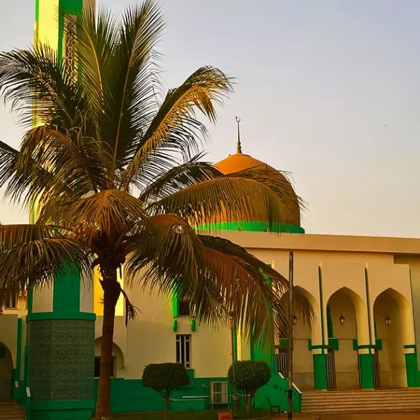 Masjid hijau dikelilingi pepohonan di bawah langit senja